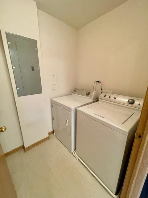 washroom with electric panel, laundry area, washing machine and dryer, and baseboards