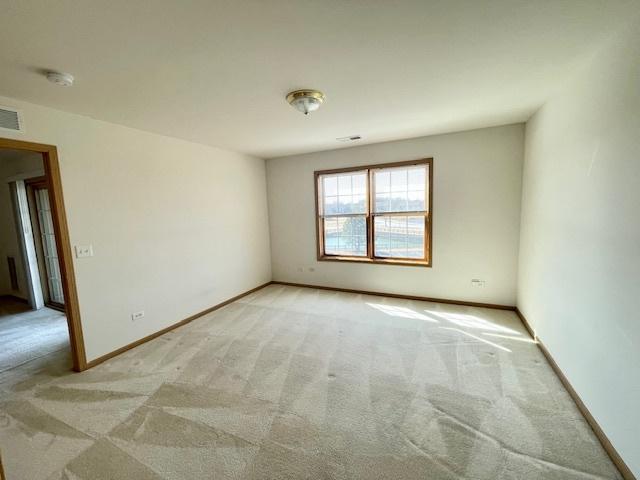 empty room featuring baseboards, light carpet, and visible vents