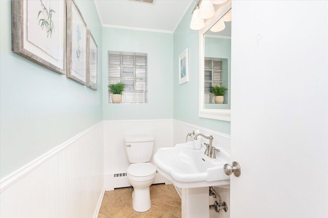 bathroom with tile patterned floors, a wainscoted wall, toilet, crown molding, and baseboard heating