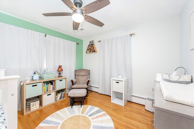 sitting room with baseboard heating, visible vents, ceiling fan, and wood finished floors