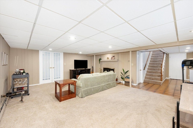 carpeted living room with a drop ceiling, recessed lighting, a brick fireplace, and stairs