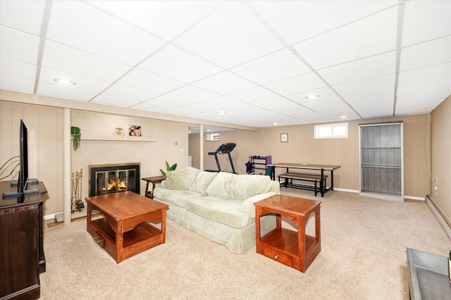 living area featuring a drop ceiling, a fireplace, baseboards, and carpet