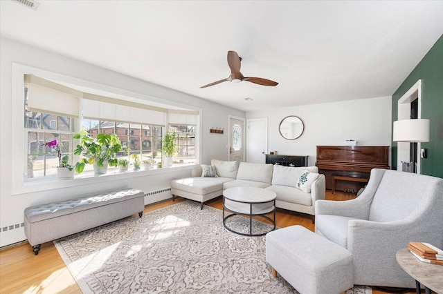 living room featuring a baseboard radiator, wood finished floors, and a ceiling fan