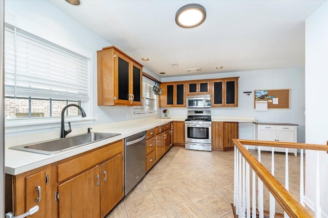 kitchen with brown cabinetry, appliances with stainless steel finishes, light countertops, and a sink