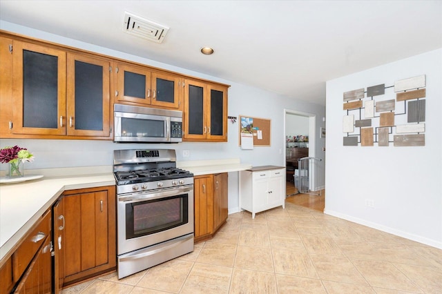 kitchen with stainless steel appliances, visible vents, brown cabinetry, and light countertops