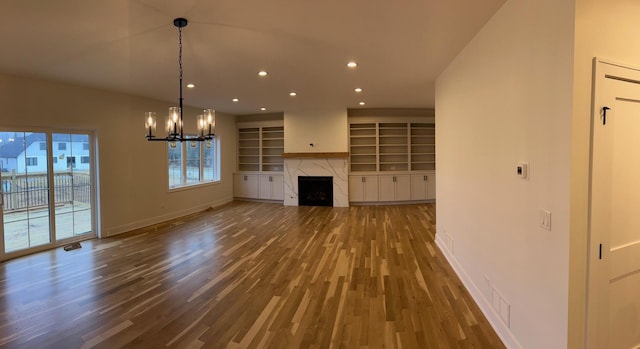 unfurnished living room featuring recessed lighting, wood finished floors, baseboards, and a premium fireplace