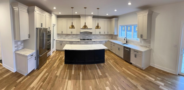 kitchen with a sink, stainless steel appliances, light wood-type flooring, and a center island