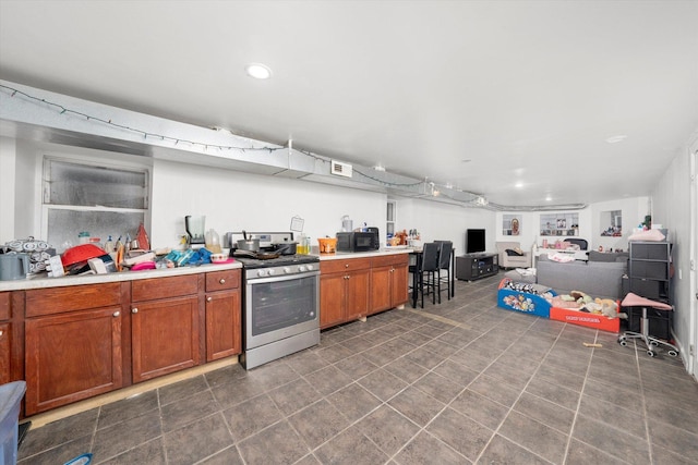 kitchen with brown cabinetry, light countertops, black microwave, gas range, and open floor plan