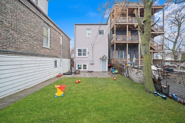 rear view of house featuring a patio, a lawn, and fence