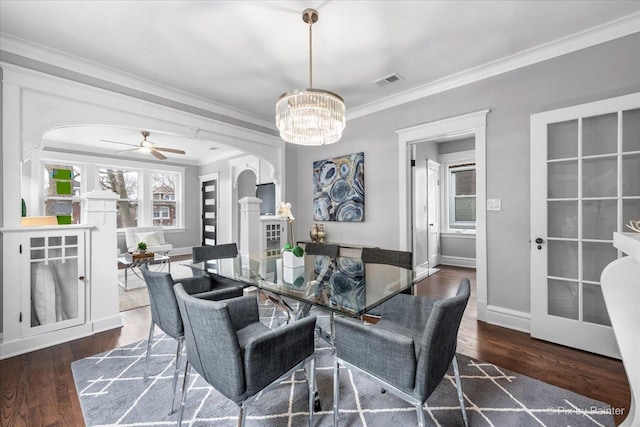 dining space featuring visible vents, wood finished floors, arched walkways, crown molding, and baseboards