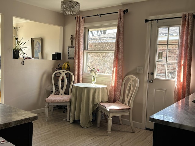 dining area with a wealth of natural light, light wood-type flooring, and baseboards