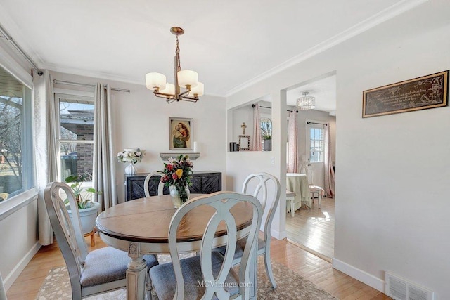 dining space with baseboards, visible vents, light wood finished floors, an inviting chandelier, and crown molding