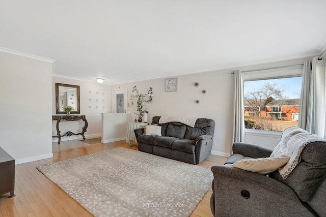 living room with crown molding, baseboards, and light wood-type flooring