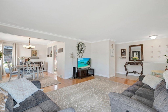 living room featuring a notable chandelier, crown molding, light wood-type flooring, and baseboards