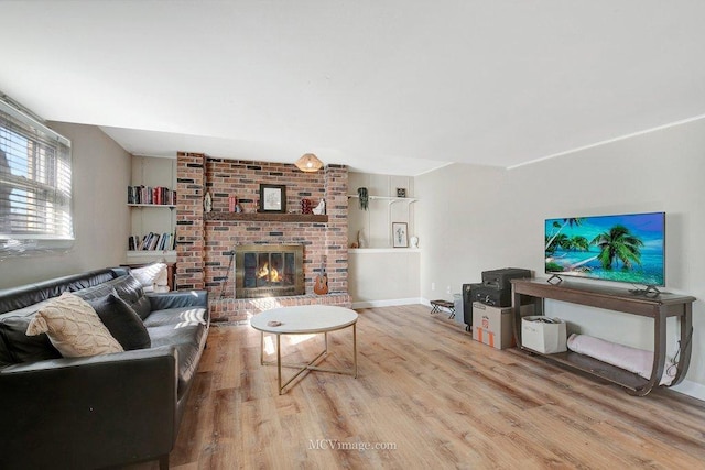 living room with a brick fireplace, wood finished floors, and baseboards