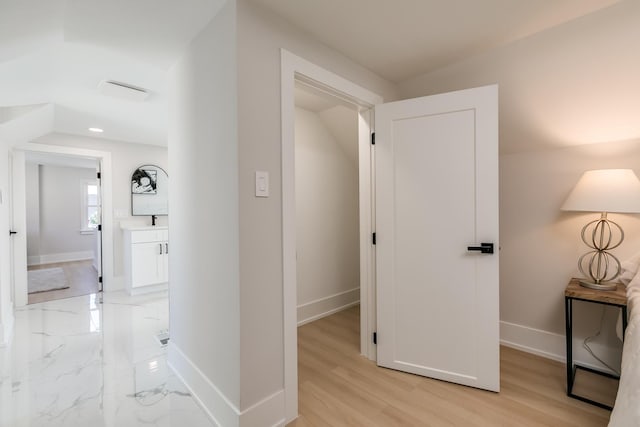 hallway featuring baseboards and vaulted ceiling