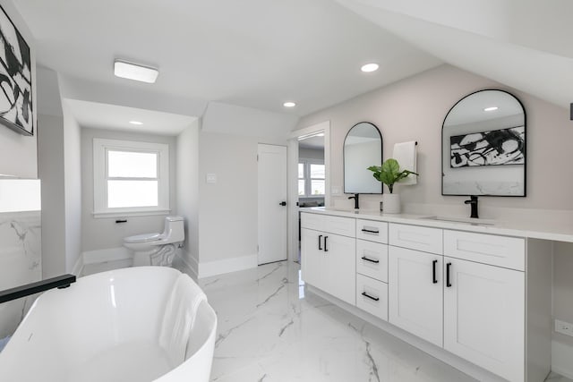 full bathroom with baseboards, double vanity, a freestanding bath, a sink, and marble finish floor