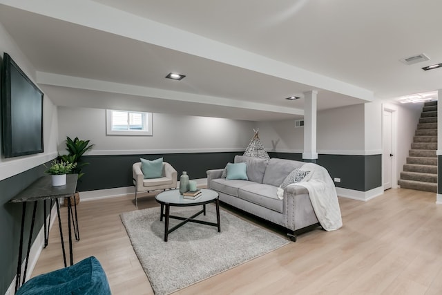 living room with stairs, visible vents, light wood-type flooring, and baseboards