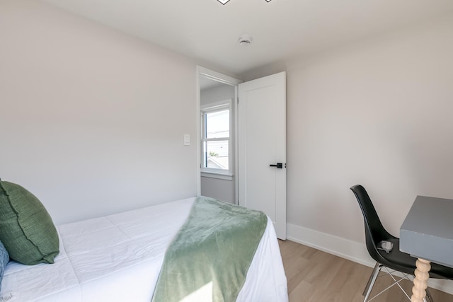 bedroom with light wood finished floors and baseboards