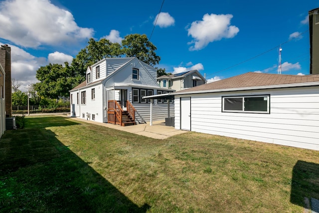 rear view of property with central air condition unit and a yard