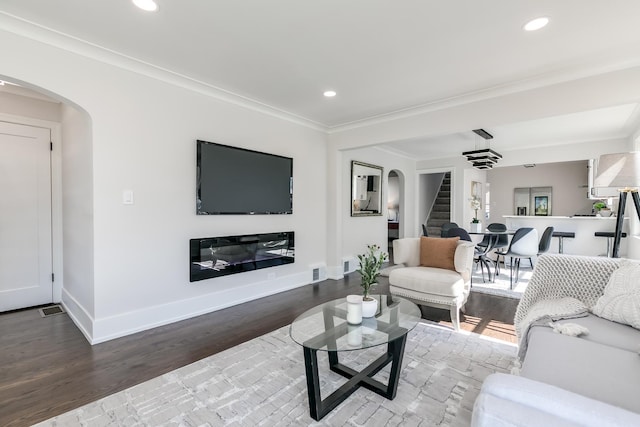 living room with baseboards, arched walkways, stairs, and crown molding