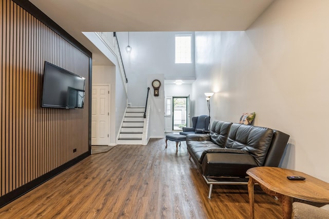 living area with stairway, baseboards, wood finished floors, and a towering ceiling