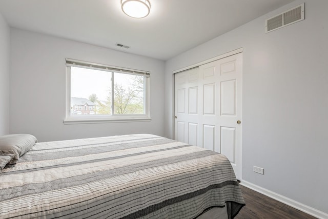 bedroom with baseboards, visible vents, dark wood-style floors, and a closet