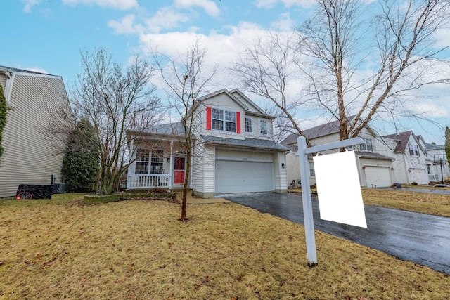 traditional home featuring a front yard, an attached garage, covered porch, and driveway