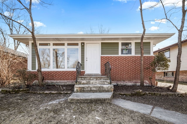 bungalow featuring brick siding