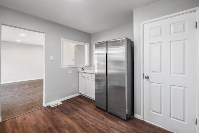 kitchen featuring visible vents, dark wood finished floors, freestanding refrigerator, white cabinets, and baseboards