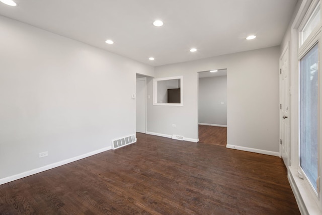 spare room featuring dark wood-type flooring, recessed lighting, visible vents, and baseboards