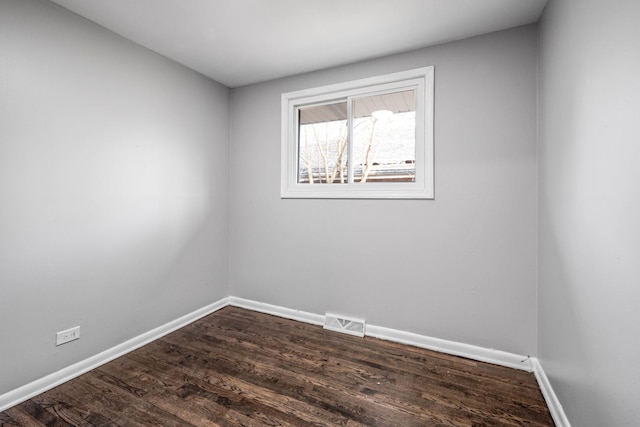 unfurnished room with visible vents, baseboards, and dark wood finished floors