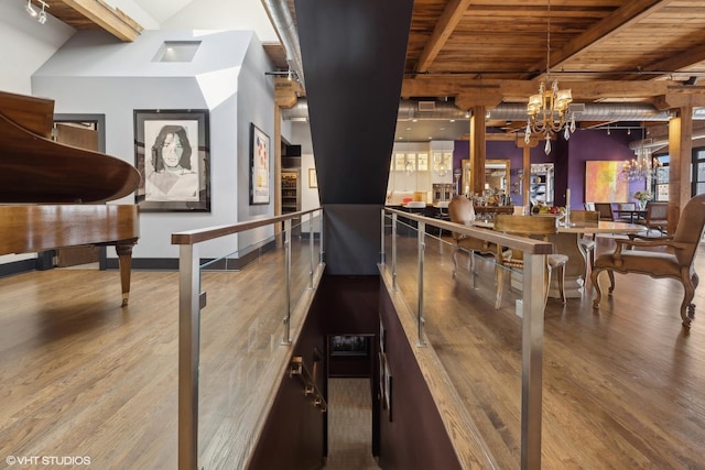 dining area featuring beam ceiling, a notable chandelier, wood finished floors, and wooden ceiling