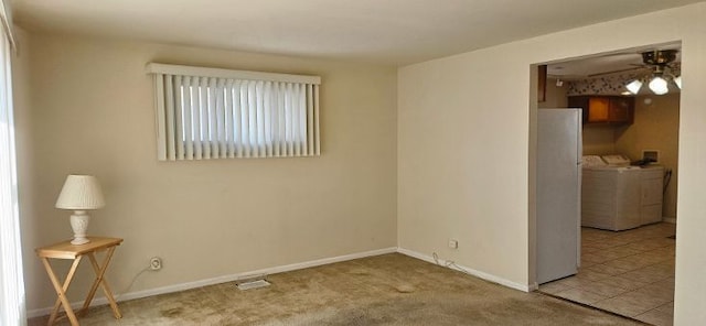 empty room featuring a ceiling fan, carpet, baseboards, and washer and clothes dryer