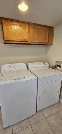 washroom featuring light tile patterned floors, cabinet space, and washing machine and dryer