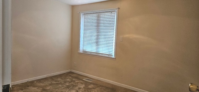 empty room featuring dark colored carpet, visible vents, and baseboards