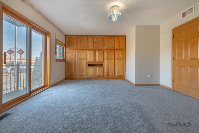 interior space featuring visible vents, baseboards, light colored carpet, and an inviting chandelier