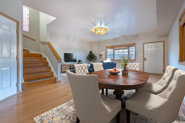 dining space with stairs and light wood-style flooring