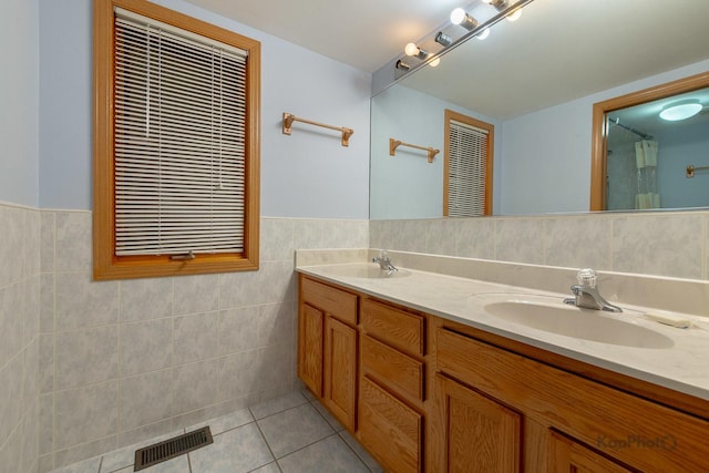 full bathroom featuring tile patterned flooring, tile walls, visible vents, and a sink