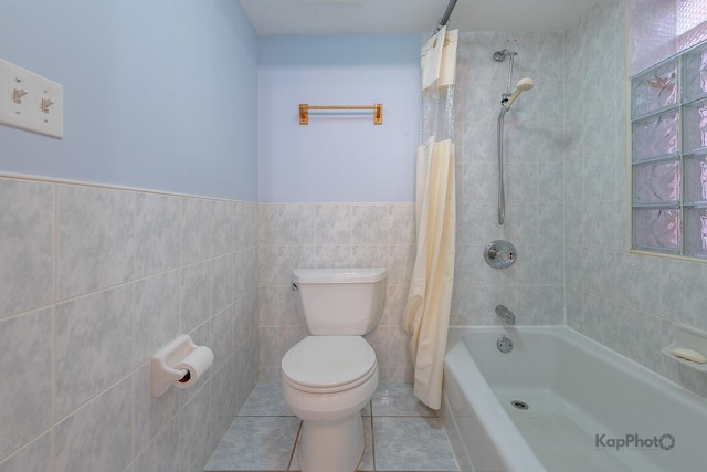 full bathroom featuring shower / bathtub combination with curtain, a wainscoted wall, tile patterned floors, toilet, and tile walls