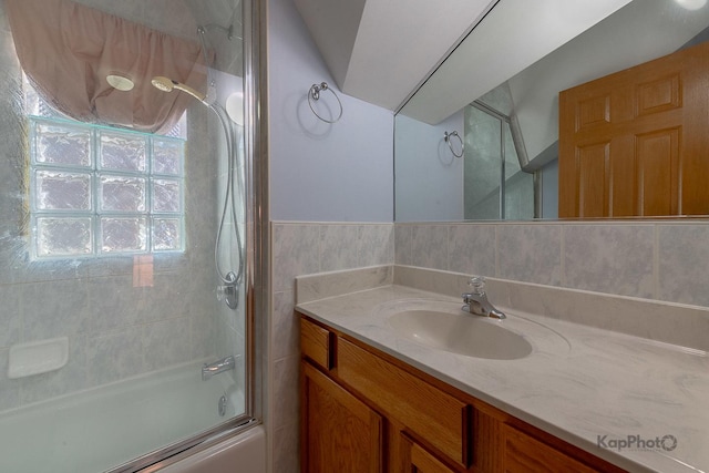 bathroom featuring enclosed tub / shower combo, tile walls, and vanity