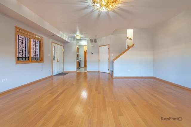 unfurnished living room featuring visible vents, baseboards, an inviting chandelier, and light wood finished floors