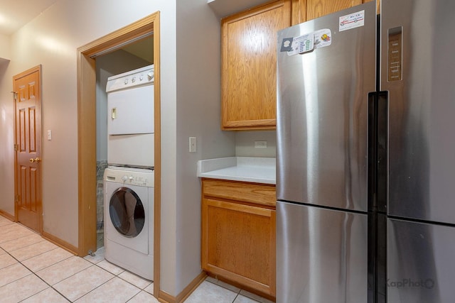 laundry area featuring light tile patterned floors, baseboards, laundry area, and stacked washer / dryer