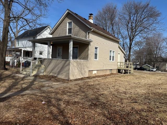 view of side of home featuring covered porch and a chimney