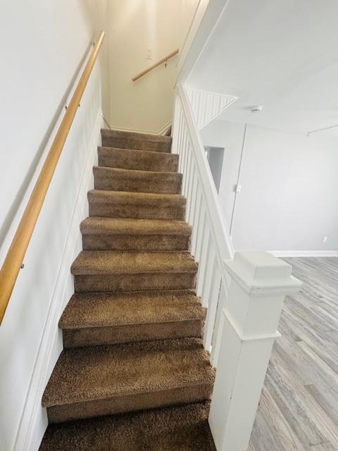 staircase featuring wood finished floors and baseboards