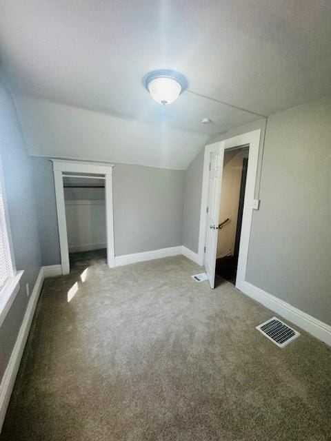 unfurnished bedroom featuring carpet, lofted ceiling, baseboards, and visible vents