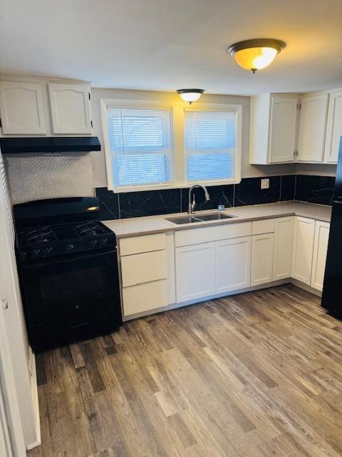 kitchen featuring a sink, white cabinetry, black appliances, and light wood finished floors