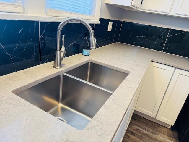 interior details featuring white cabinetry, dark wood finished floors, tasteful backsplash, and a sink