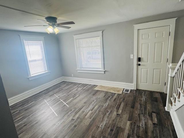 foyer entrance featuring visible vents, dark wood-type flooring, ceiling fan, baseboards, and stairway