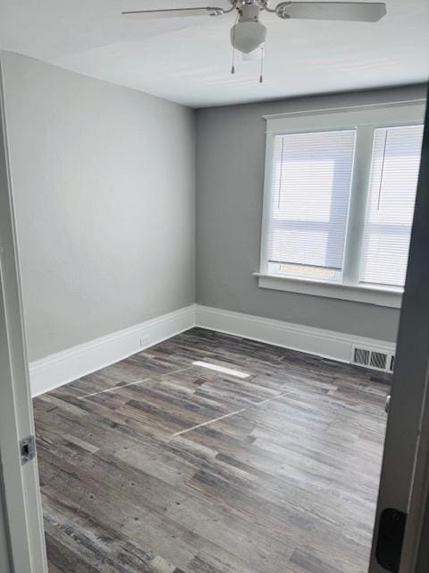 spare room featuring visible vents, ceiling fan, baseboards, and wood finished floors